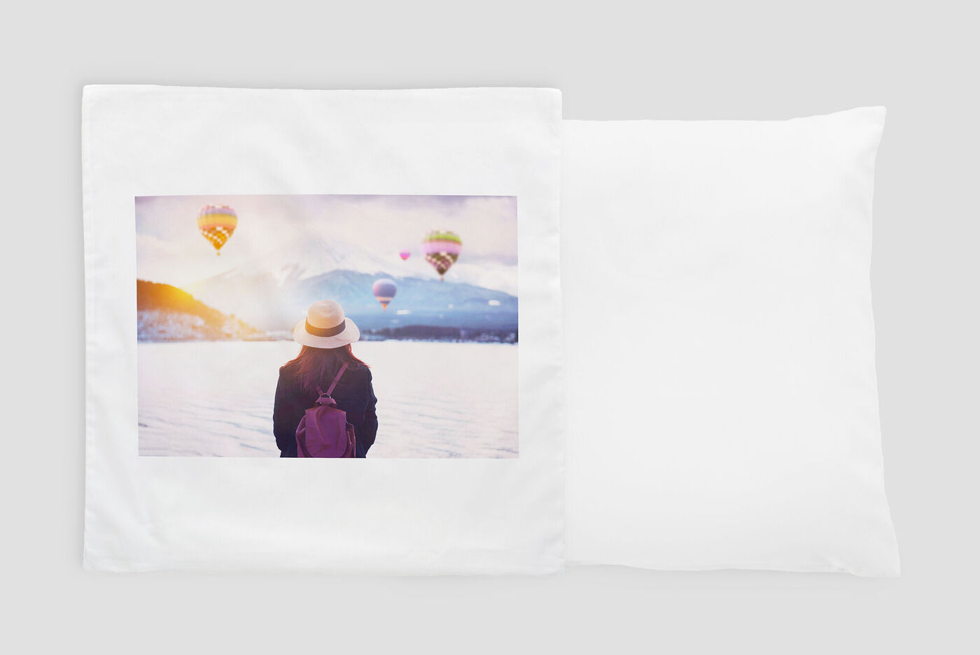 Una donna con cappello guarda un paesaggio con mongolfiere colorate nel cielo.