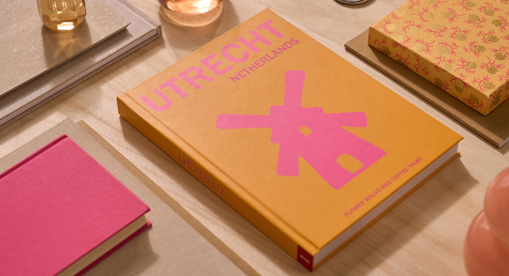 Un fotolibro CEWE è su un tavolo. La copertina è arancione e riporta la scritta "Utrecht".