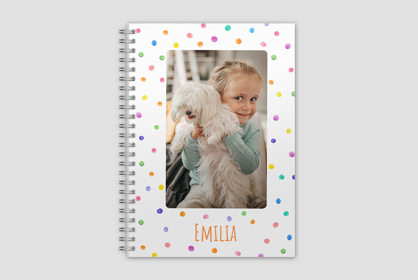 Un bambino felice tiene un piccolo cane bianco in un ambiente colorato a pois