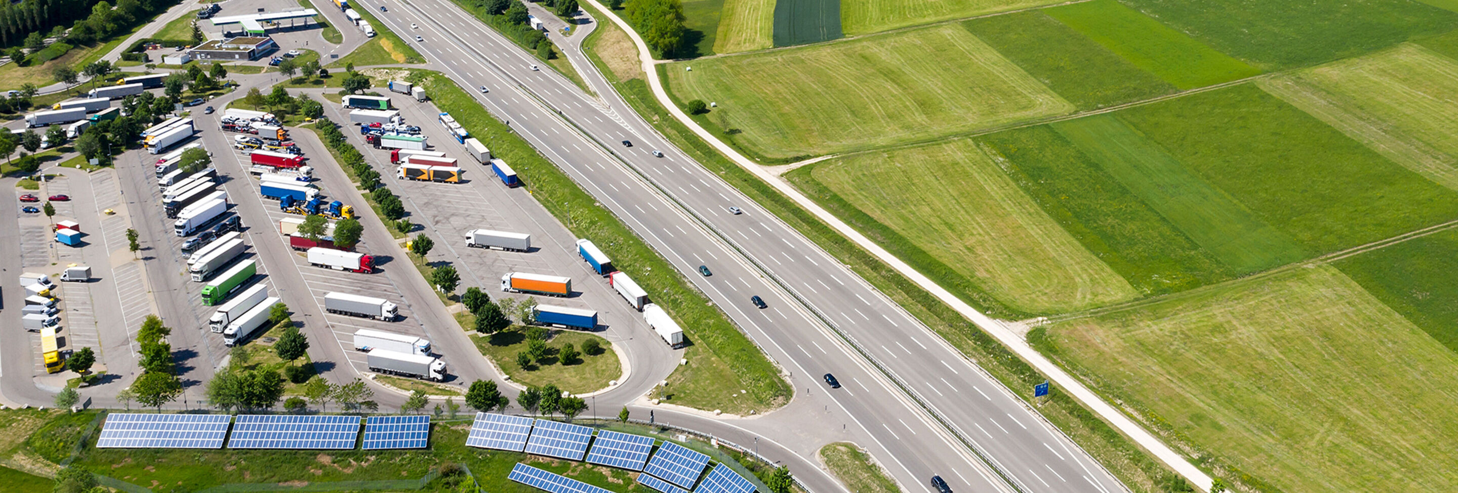 Vista aerea di un'autostrada con parcheggio per camion e pannelli solari
