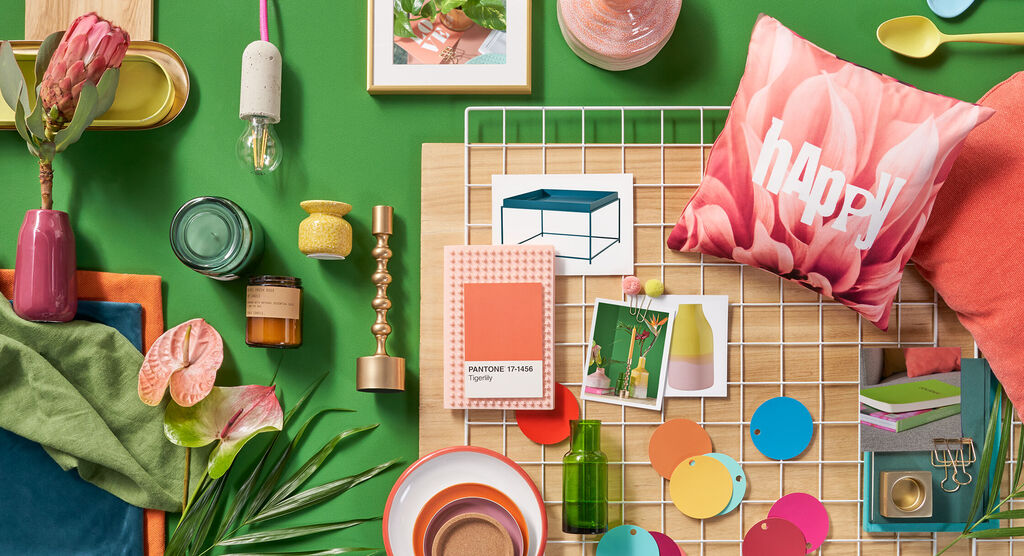 Varietà di elementi decorativi colorati raccolti su un tavolo in legno, tra cui vasi e cuscini con la scritta "happy".