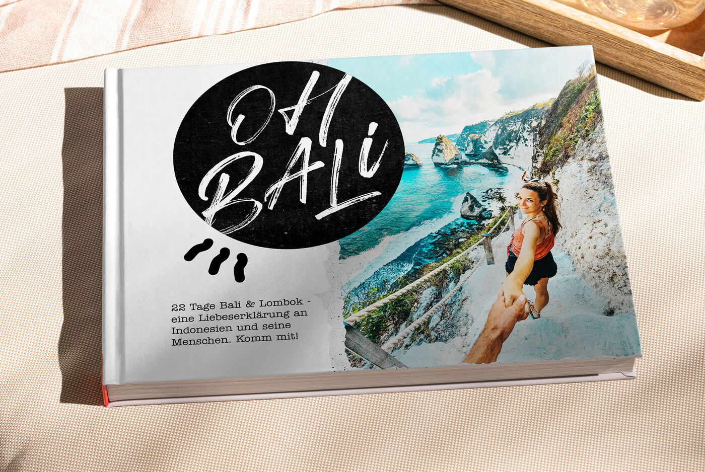 Un fotolibro creativo chiamato 'Oh Bali' su un tavolo, donna corre verso la costa sorridendo.