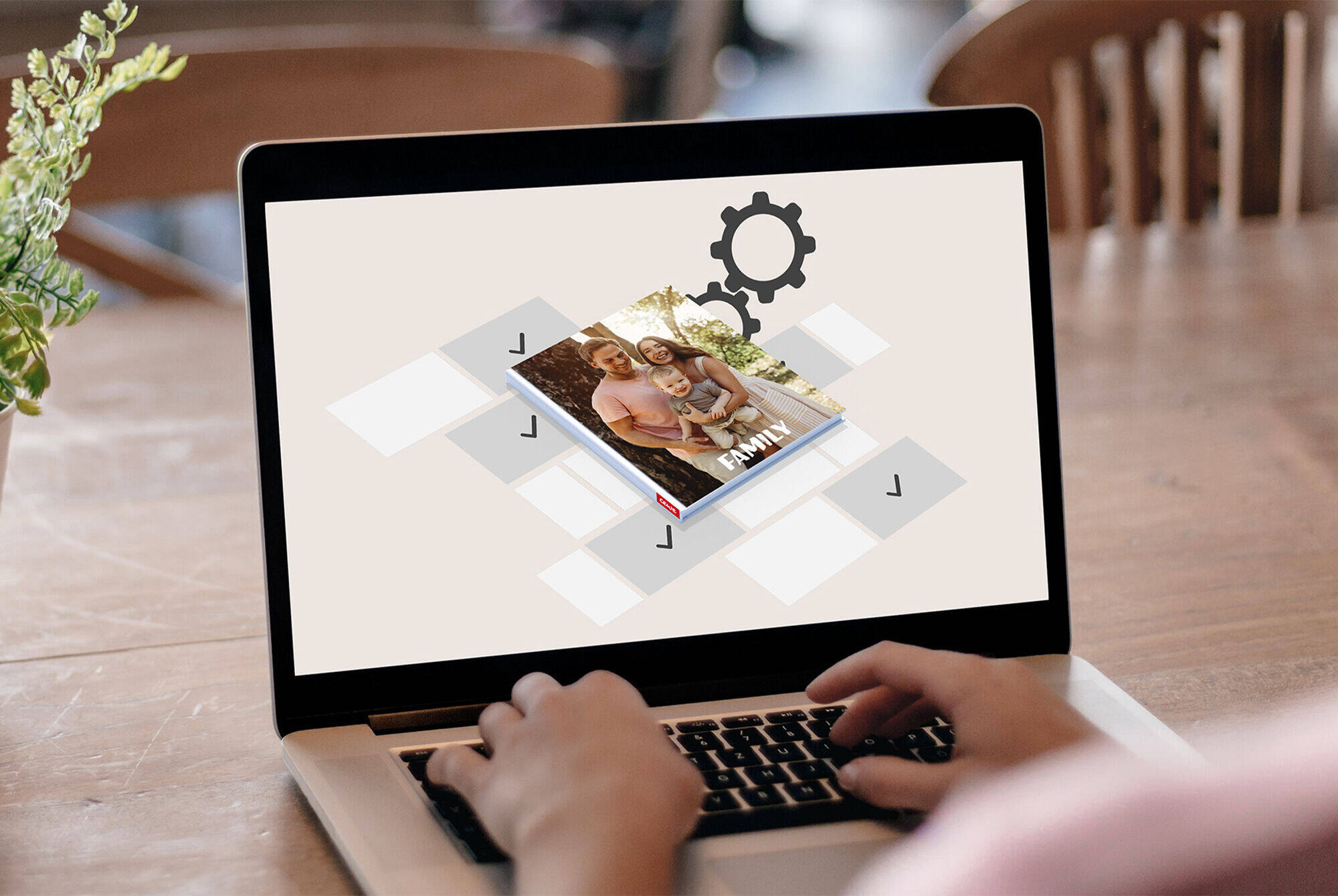 Persona crea un fotolibro CEWE su un laptop con un'interfaccia creativa.