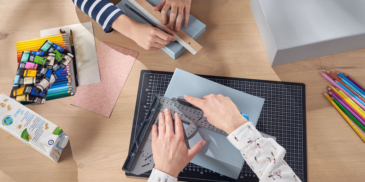 Due persone lavorano su progetti creativi con materiali vari su un tavolo
