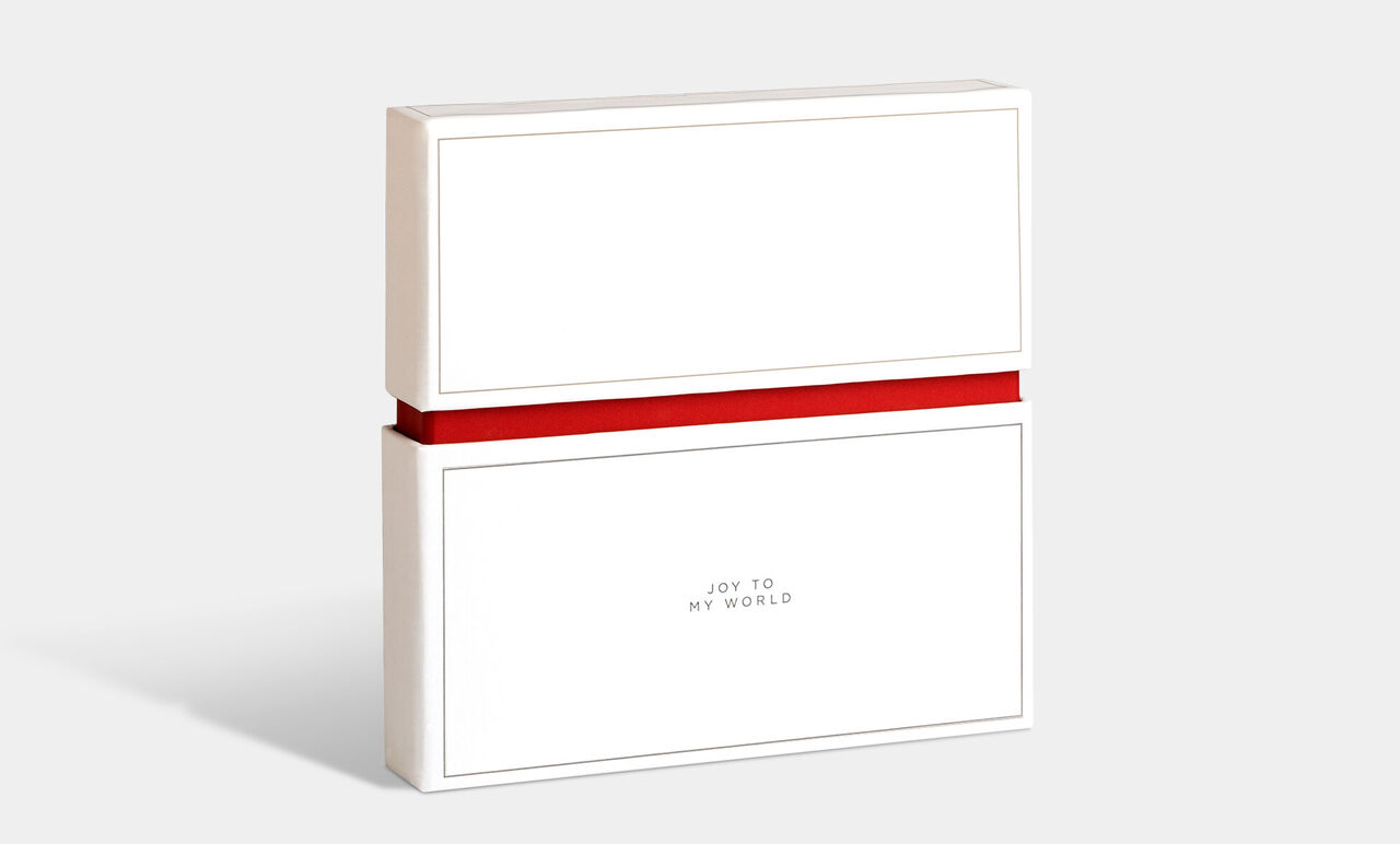 Confezione regalo bianca con nastro rosso, etichettata 'Joy to my world'