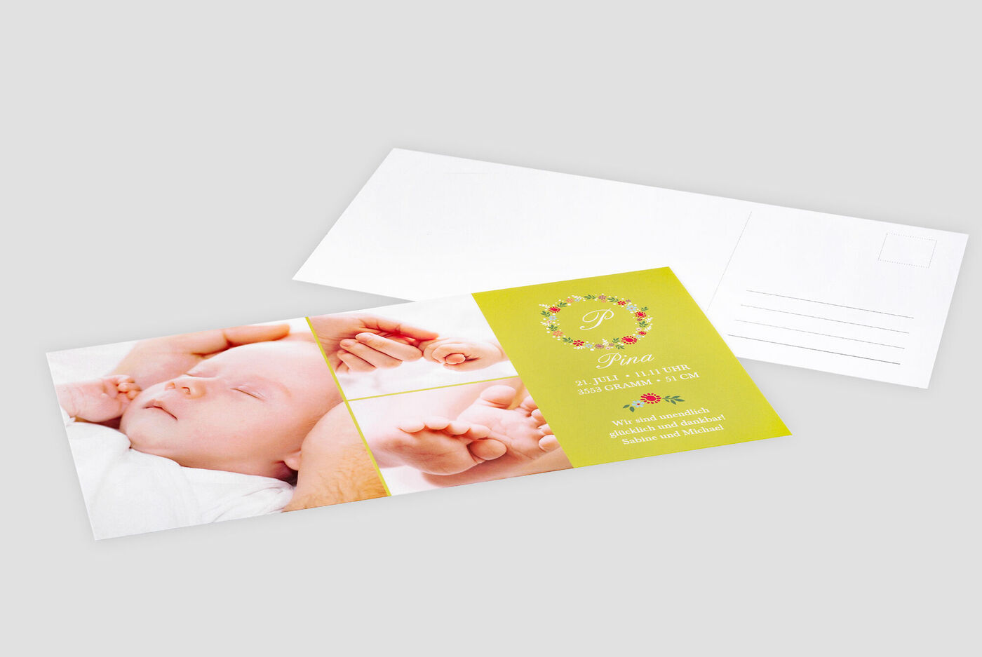 Una cartolina CEWE personalizzata mostra un dolce bambino tra le braccia dei genitori. Decorata con fiori colorati e un testo affettuoso.