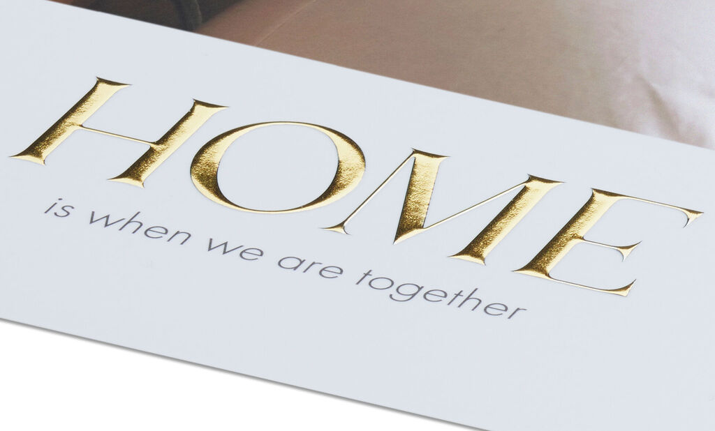 Quadro murale con la scritta 'HOME è quando siamo insieme' in oro e grigio.