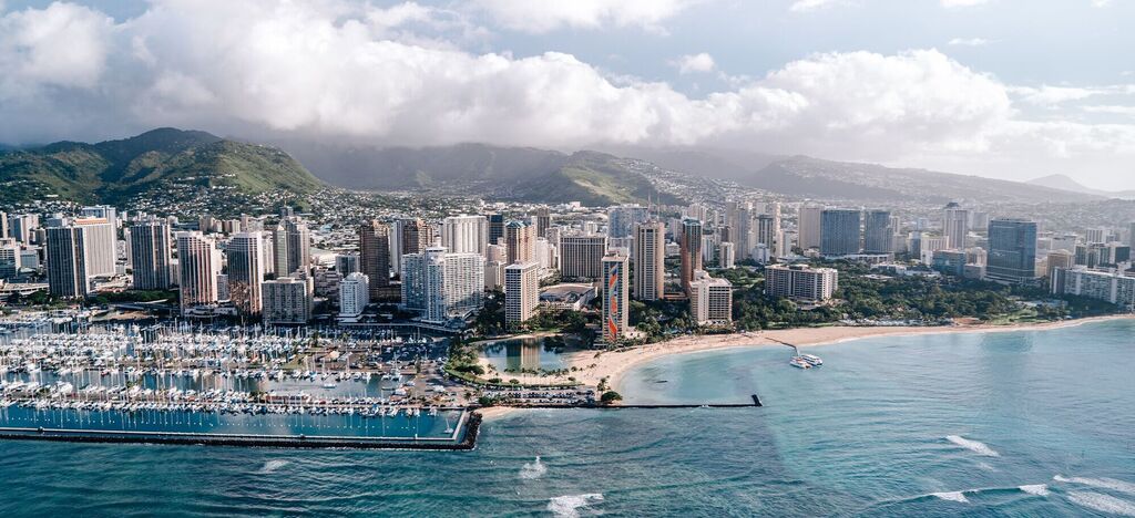 Veduta aerea di Honolulu con grattacieli, spiaggia e porto.