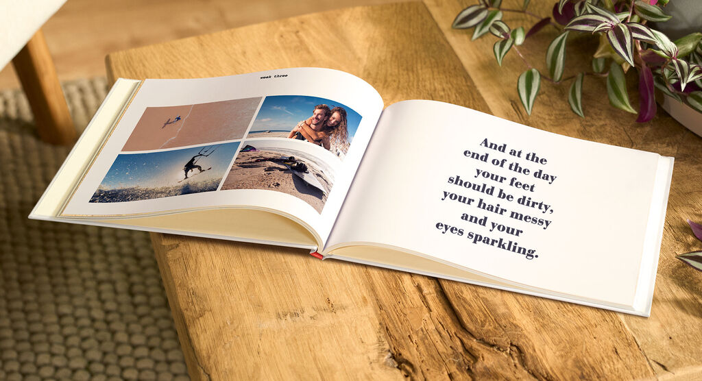 Fotolibro CEWE aperto su un tavolo, con foto di una vacanza al mare e una pagina di testo ispiratrice.