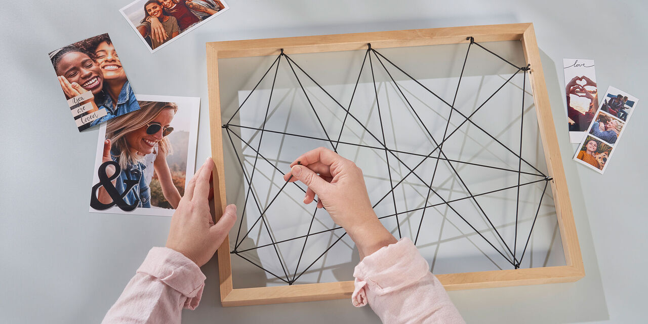 Un'immagine creativa mostra una persona che stende cavi da una cornice decorativa attorno a foto. Nasce un'opera d'arte unica.