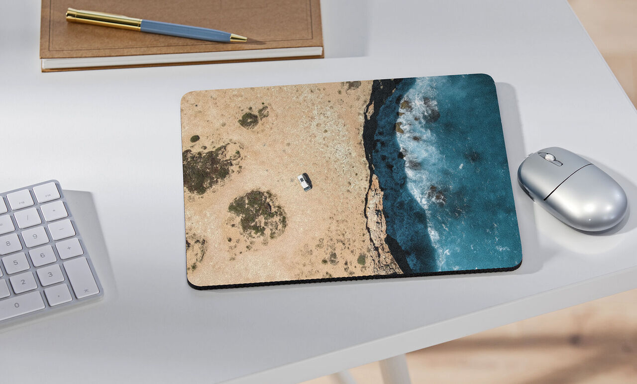 Un elegante tappetino per il mouse con vista aerea di una costa. La spiaggia di sabbia si incontra con il mare blu.