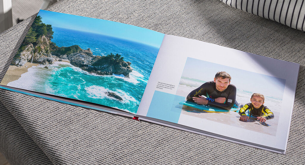 Un bellissimo CEWE FOTOLIBRO su un tavolo con una spiaggia e una foto di famiglia che ricorda momenti indimenticabili.