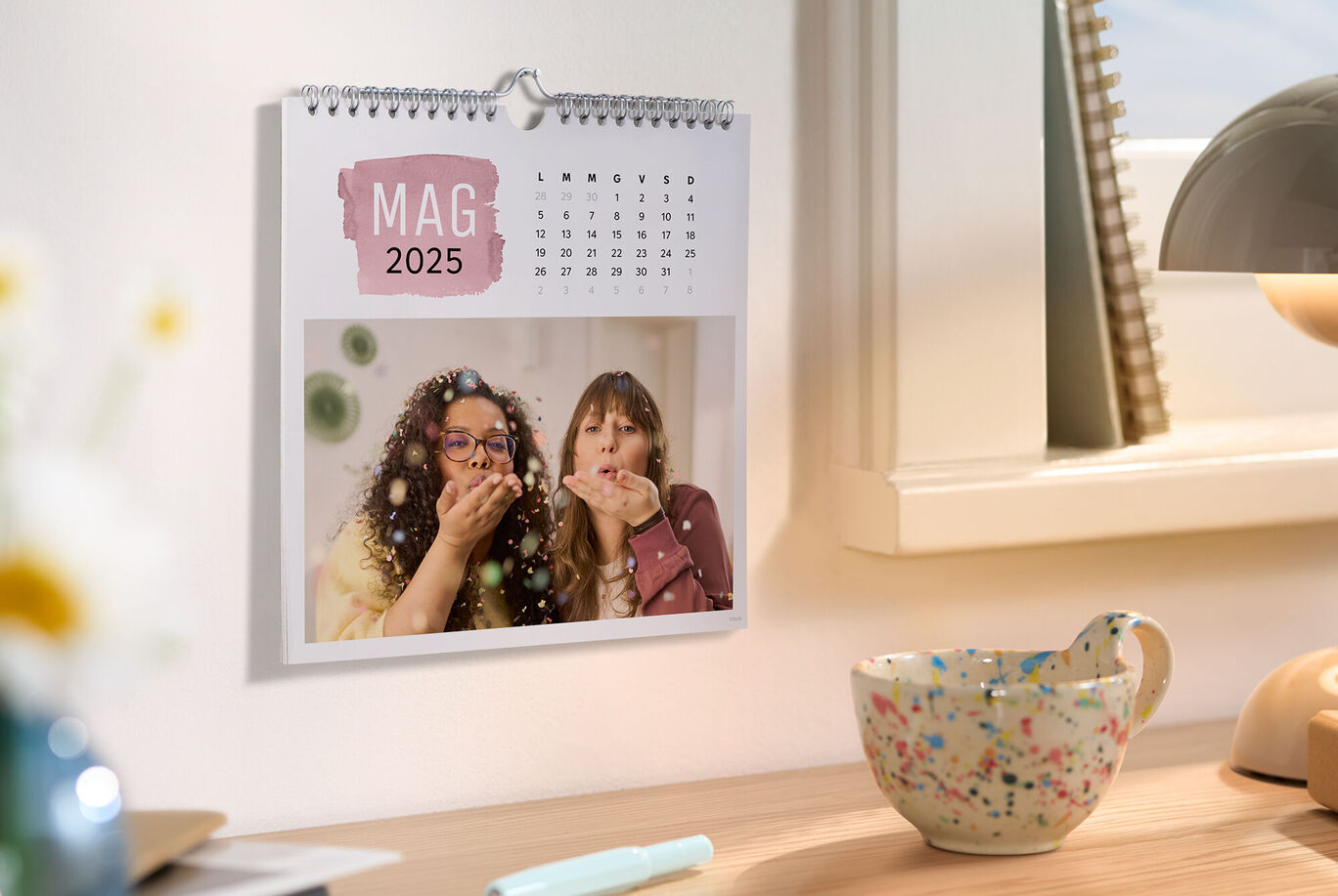 Calendario da parete per maggio 2025 appeso con dettagli colorati.