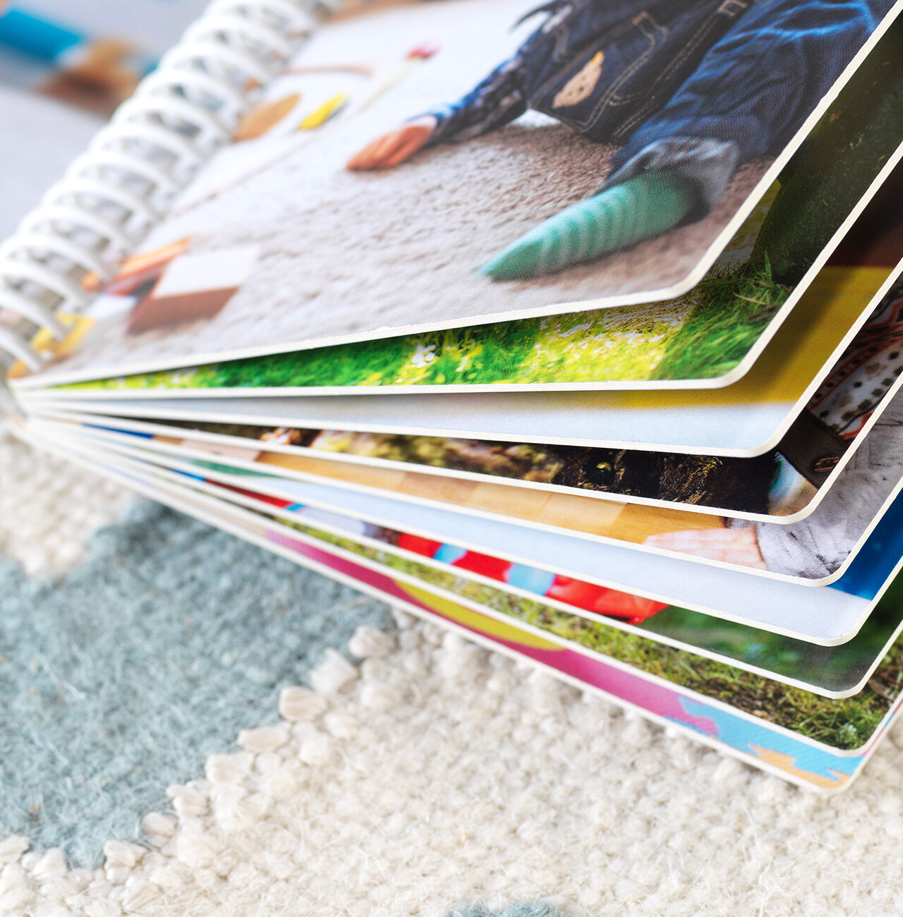 Dettaglio di un fotolibro aperto con pagine colorate su un tappeto.