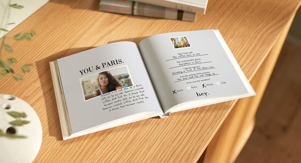 Un fotolibro aperto mostra una pagina personalizzata con testo e una foto su un tavolo di legno.