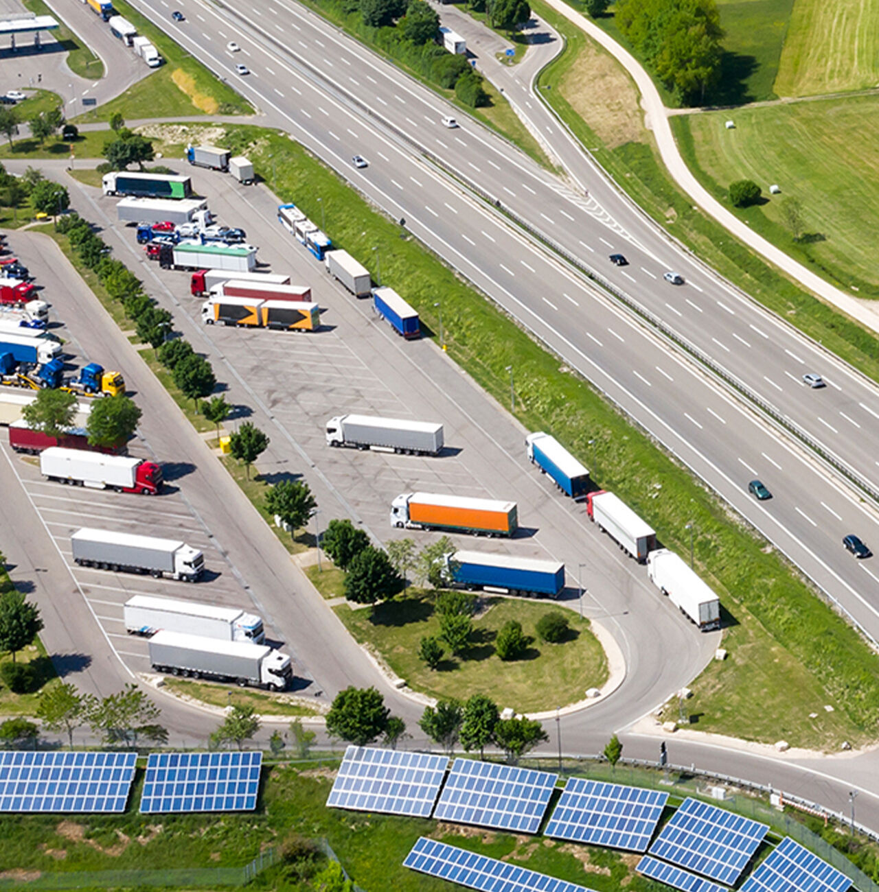 Ripresa aerea di un parcheggio con molti camion e pannelli solari.