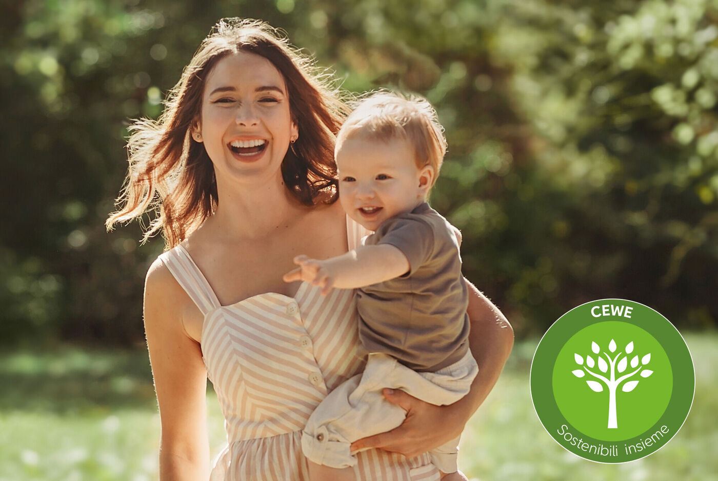 Una madre tiene il suo bambino all'aperto mostrando qualcosa di interessante. Il sole splende sullo sfondo verde.
